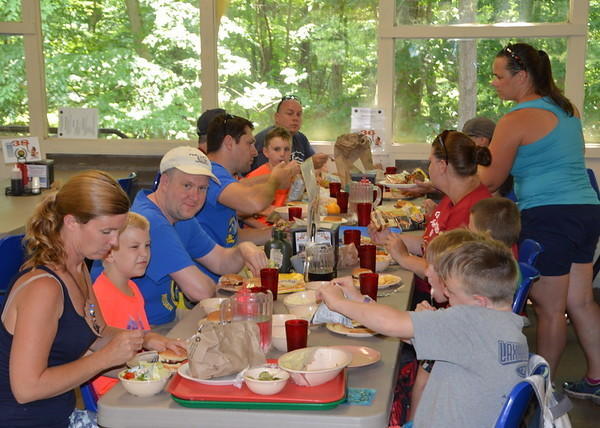 Young scouts and their parents eating hamburgers around a table in a dining hall