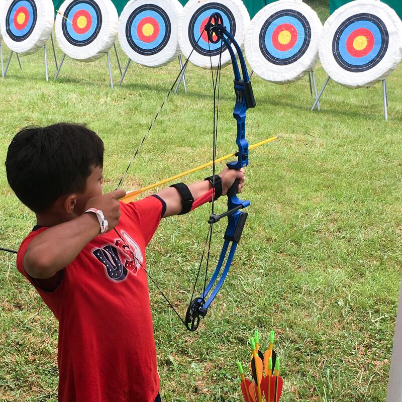 A boy wih a bow and arrow preparing to loose the arrow at a target