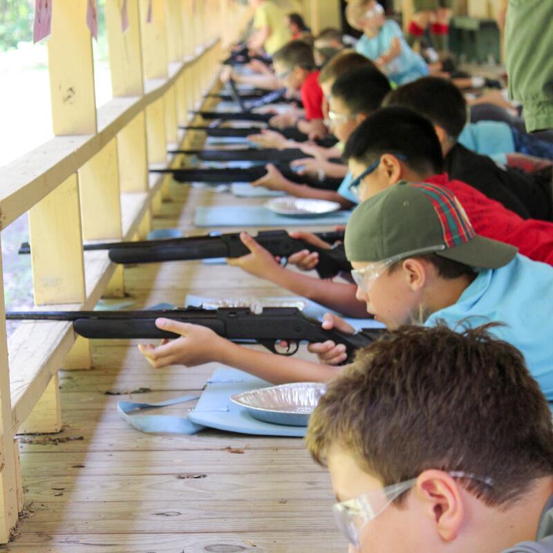 A group of scouts shooting BB guns on the firing line of a rifle range