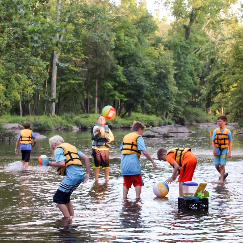 A small group of scouts wanders ankle deep through a creek