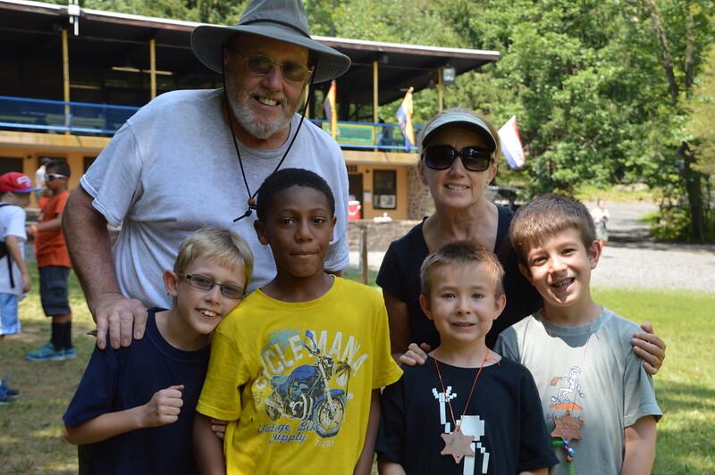 Four young boys and their two leaders smiling in front of a dining hall