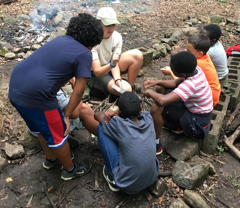 Five young scouts and a staff member lighting a fire